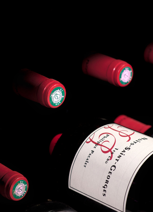Bouteilles de Nuits-Saint-Georges Philippe Pacalet couchées, capsules rouges